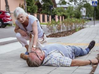 Woman checking pulse of person on the ground.