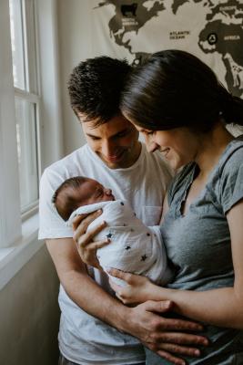 Two new parents holding their newborn baby. Photo by Kelly Sikkema on Unsplash