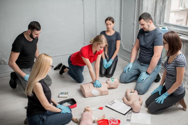 Female instructor conducting CPR in a classroom full of students