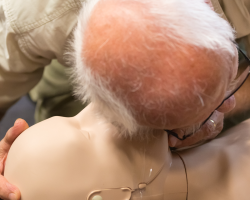 Older gentleman giving CPR to a CPR dummy