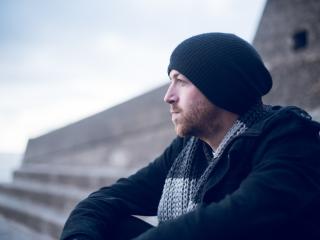 Man with slouch beanie hat pondering.